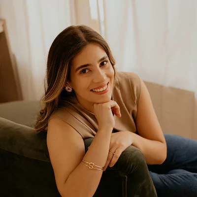 Smiling woman sitting on a couch, resting her chin on her hand.